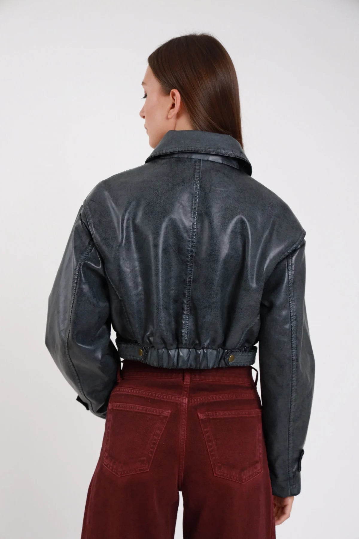 Bomber crop ecopelle washed grigio ardesia retro intera cuciture contrasto workwear orlo elastico coulisse bottoni laterali manica balloon - modella retro intera sguardo laterale basso pantaloni borgogna velluto capelli castani lisci
