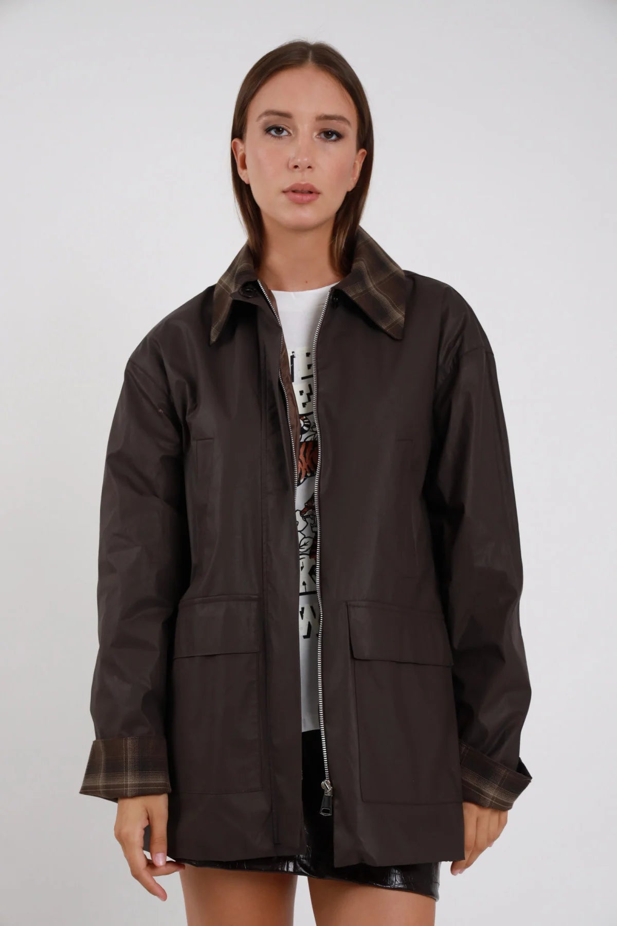 Trench Colletto Check ecopelle cerata vintage marrone cioccolato colletto check tartan zip frontale tasche pattina silhouette oversize lunga frontale intera posa statica zip aperta - modella frontale intera posa statica sguardo camera capelli castani corti sfondo bianco t-shirt grafica bianca minigonna ecopelle nera