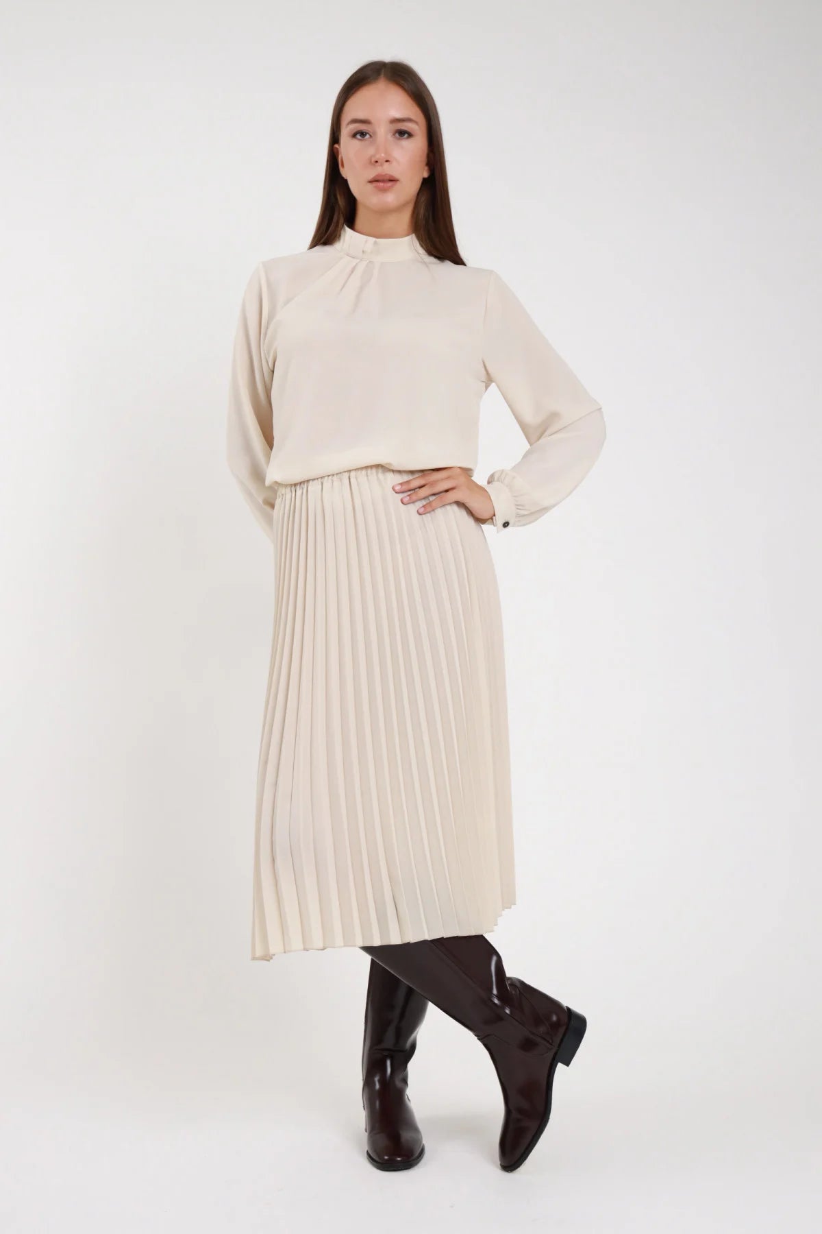 Gonna plissettata midi panna ecrù fluida vita elastica - modella frontale intera mano sul fianco sguardo frontale con blusa abbinata e stivali neri alti capelli castani lisci
