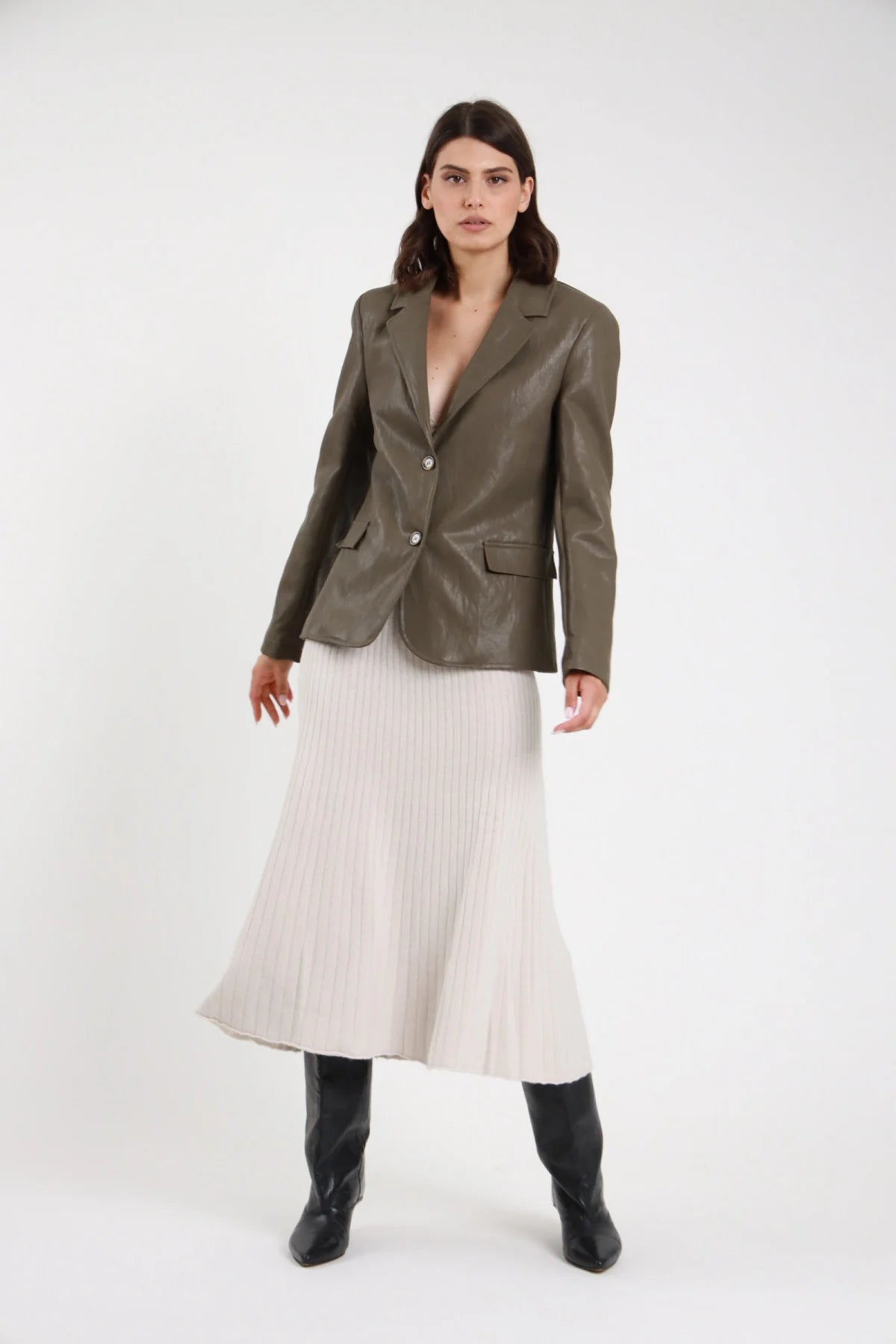 Gonna in Maglia coste ribbed panna crema vita alta silhouette sirena mermaid midi-maxi orlo svasato frontale intera - modella frontale intera mani lungo corpo sguardo frontale capelli castani sfondo bianco blazer ecopelle verde militare stivali neri al ginocchio
