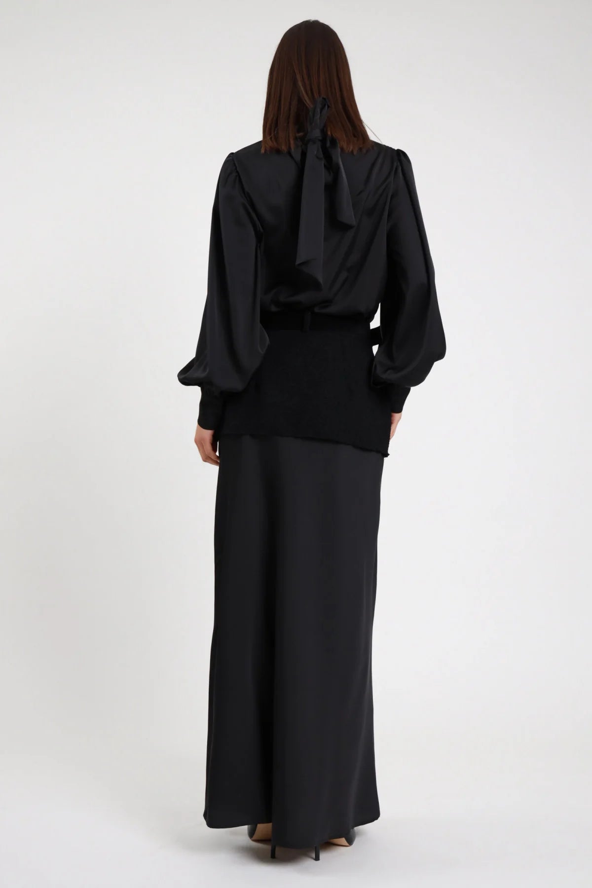 Gonna Lunga Cintura nera 100% poliestere satin lucido svasata flared molto ampia maxi floor length retro liscio satin fluido posteriore intera - modella intera posteriore capelli castani scuri lisci sfondo bianco camicia fiocco retro nera fiocco visibile décolleté neri