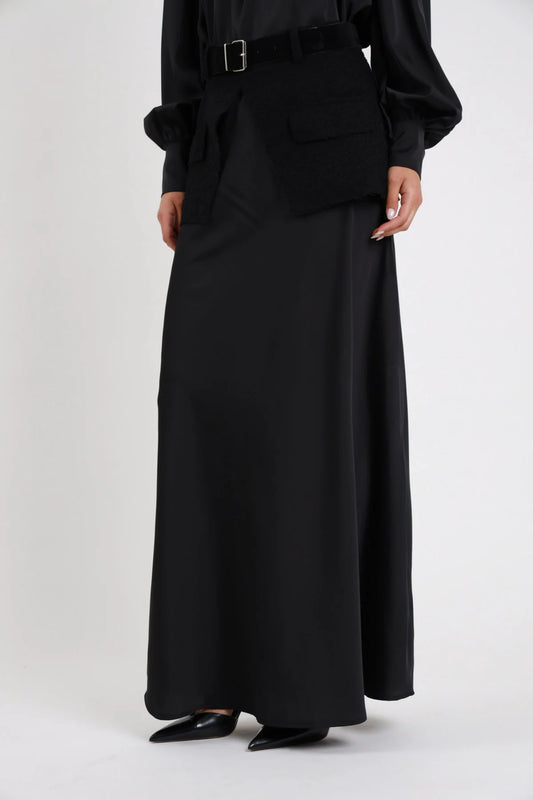 Gonna Lunga Cintura nera 100% poliestere satin lucido vita alta fascia maglia costina larga cintura pelle suede fibbia argento squadrata silhouette svasata flared maxi floor length dettaglio vita gamba frontale - modella vita gamba frontale mani laterali sfondo bianco camicia fiocco retro nera coordinata décolleté neri punta