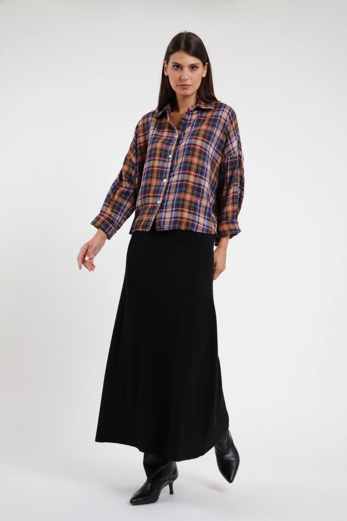 Gonna Lunga Coste nera 52% viscosa vita elastica costine verticali stretch svasata campana maxi frontale intera - modella intera frontale sguardo frontale capelli castani scuri lisci sfondo bianco camicia check tartan multicolor stivaletti neri tacco kitten