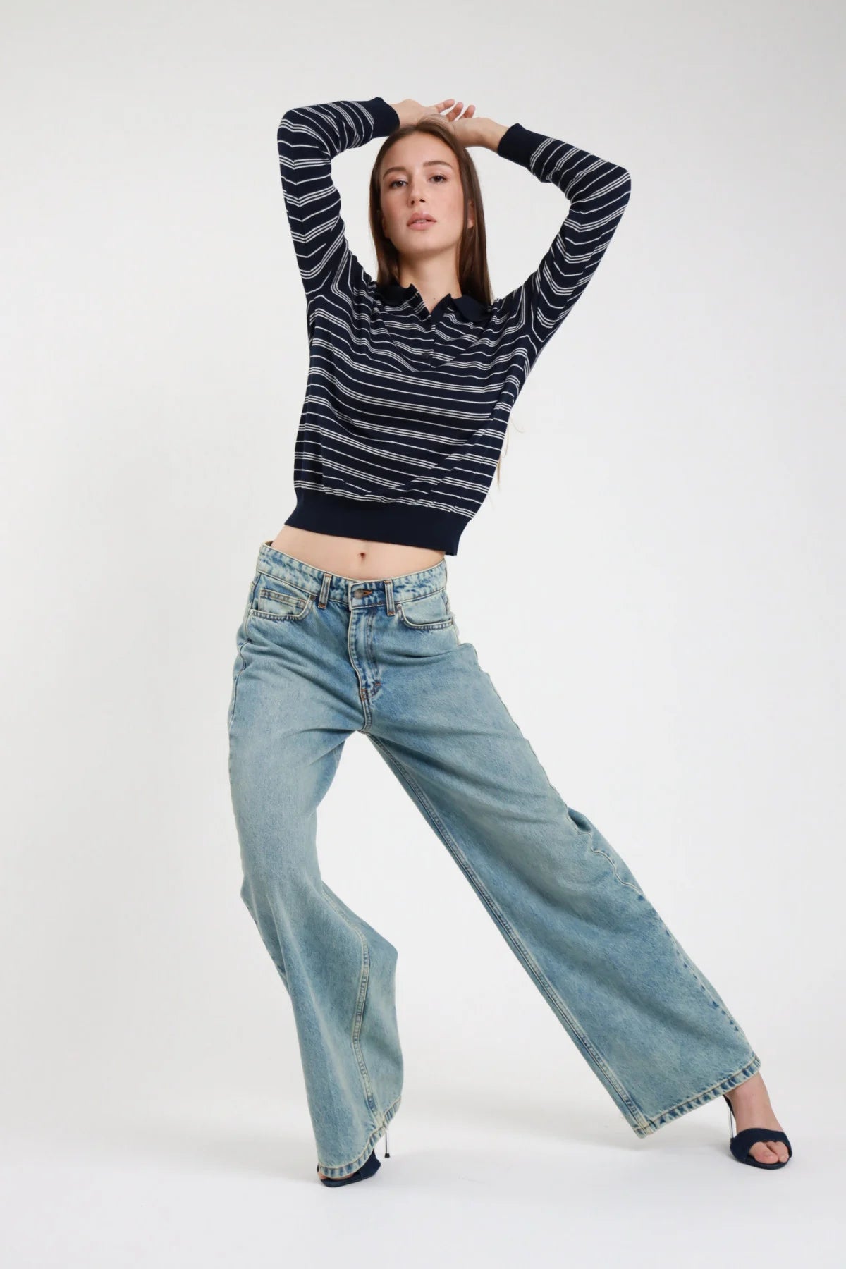 Jeans dritto wide leg palazzo blu chiaro lavato donna vita media gamba larghissima - vista frontale braccia alzate con polo righe navy e sandali neri