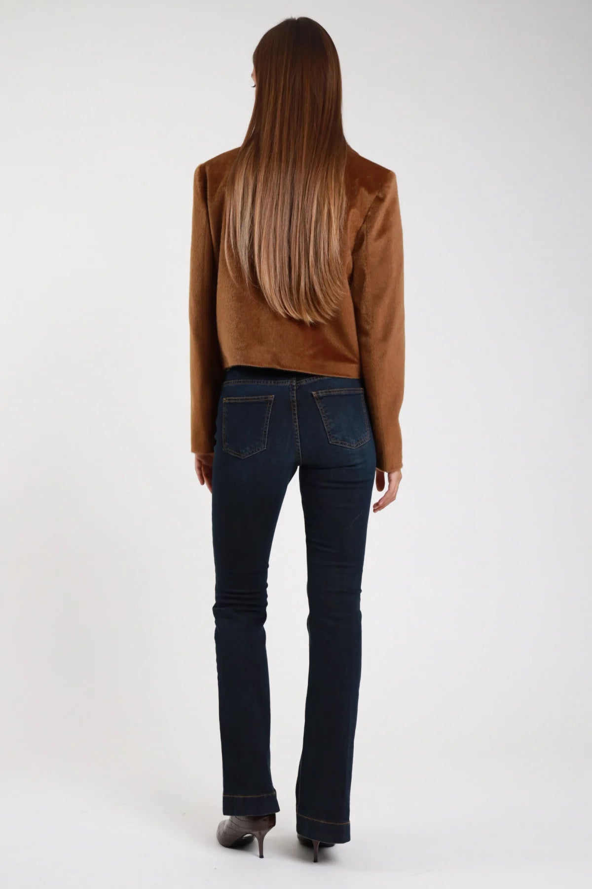 Jeans flare blu scuro svasatura bootcut tasche posteriori - modella intera retro con giacca velluto cioccolato capelli castani lisci e tacchi grigi