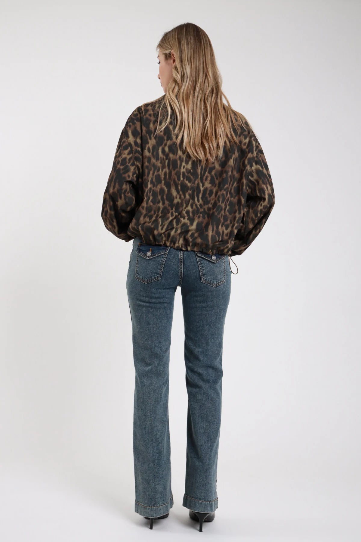 Jeans Emily flare bootcut denim vintage frontale intera vita alta gamba flare allargamento ginocchio orlo risvolto doppio mani tasche - modella frontale intera mani tasche sguardo frontale bomber animalier stivali neri capelli biondi mossi