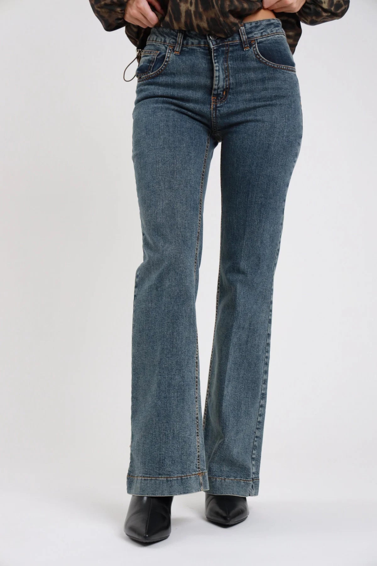 Jeans Emily flare bootcut denim vintage seduta terra tre quarti gamba flare orlo risvolto cuff doppio stivali neri - modella seduta terra laterale tre quarti mano mento sguardo laterale bomber animalier stivali neri capelli biondi lisci