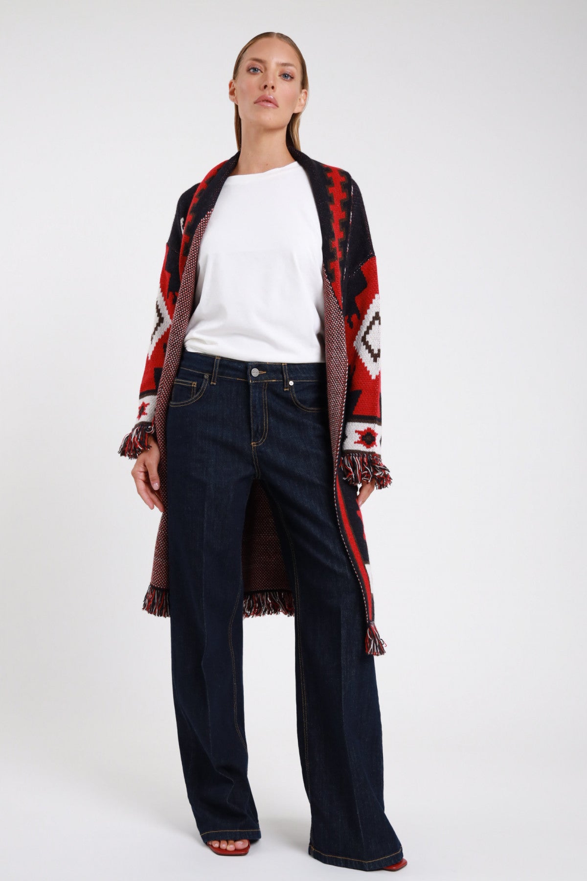 Jeans palazzo wide-leg blu indigo scuro frontale intera mid-rise silhouette ampia full-length cardigan azteco rosso nero - modella frontale intera sguardo frontale t-shirt bianca cardigan azteco frange sandali rossi capelli castani raccolti