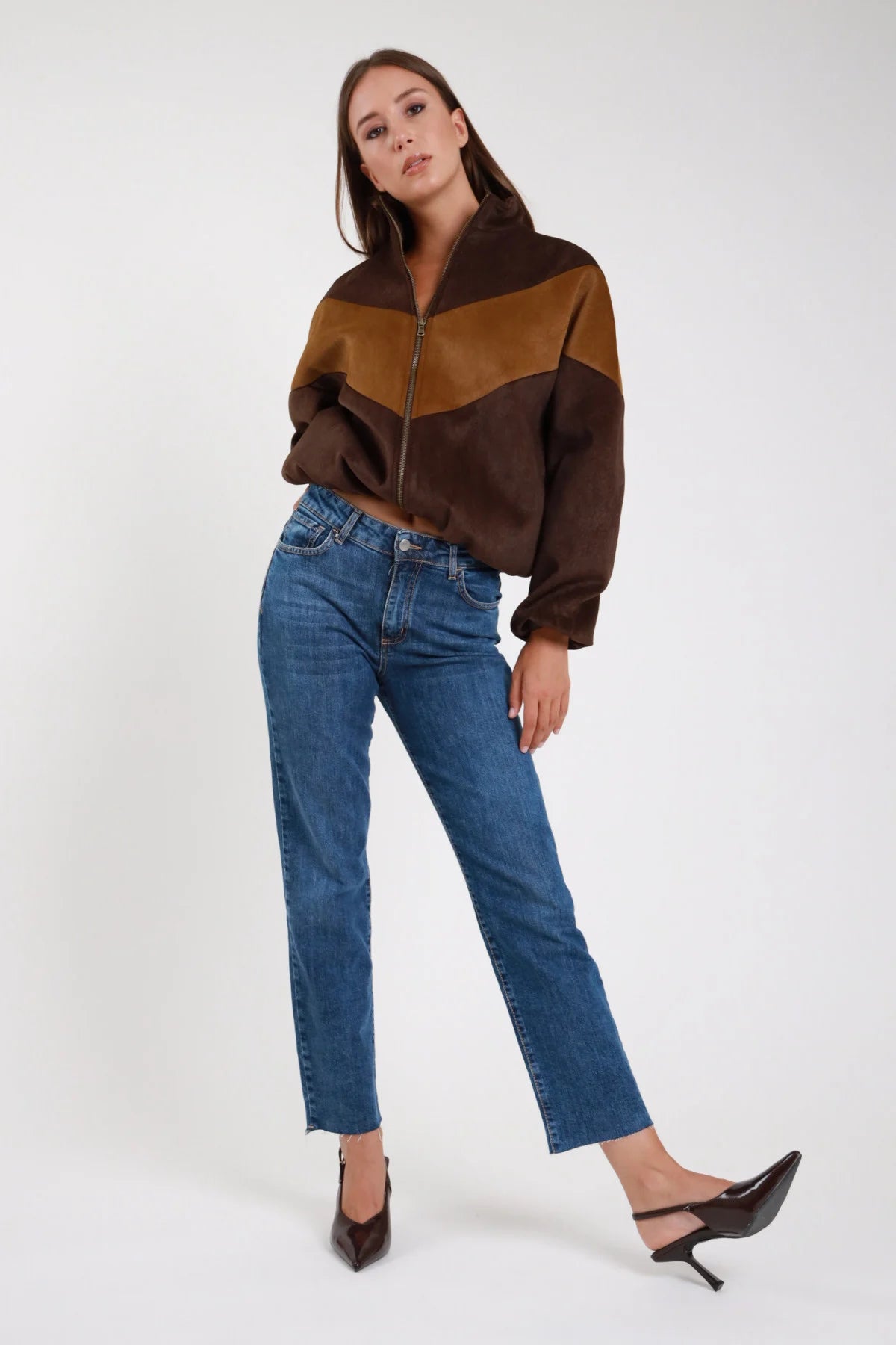Jeans regular denim medio blu indaco vita alta gamba dritta orlo grezzo frontale intera - modella frontale intera mani in tasca sguardo frontale giubbino ecopelle bicolore cioccolato camel tacchi marroni capelli castani