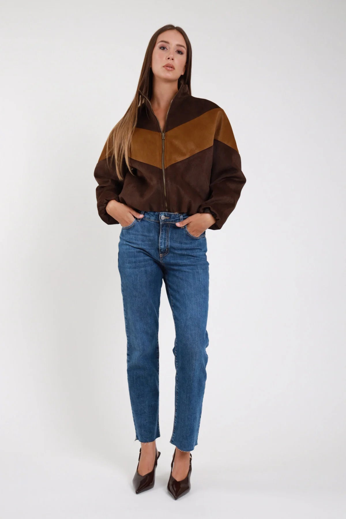 Jeans regular denim stretch straight orlo sfrangiato tre quarti dinamico - modella tre quarti passo dinamico sguardo frontale giubbino ecopelle bicolore cioccolato camel tacchi marroni capelli castani