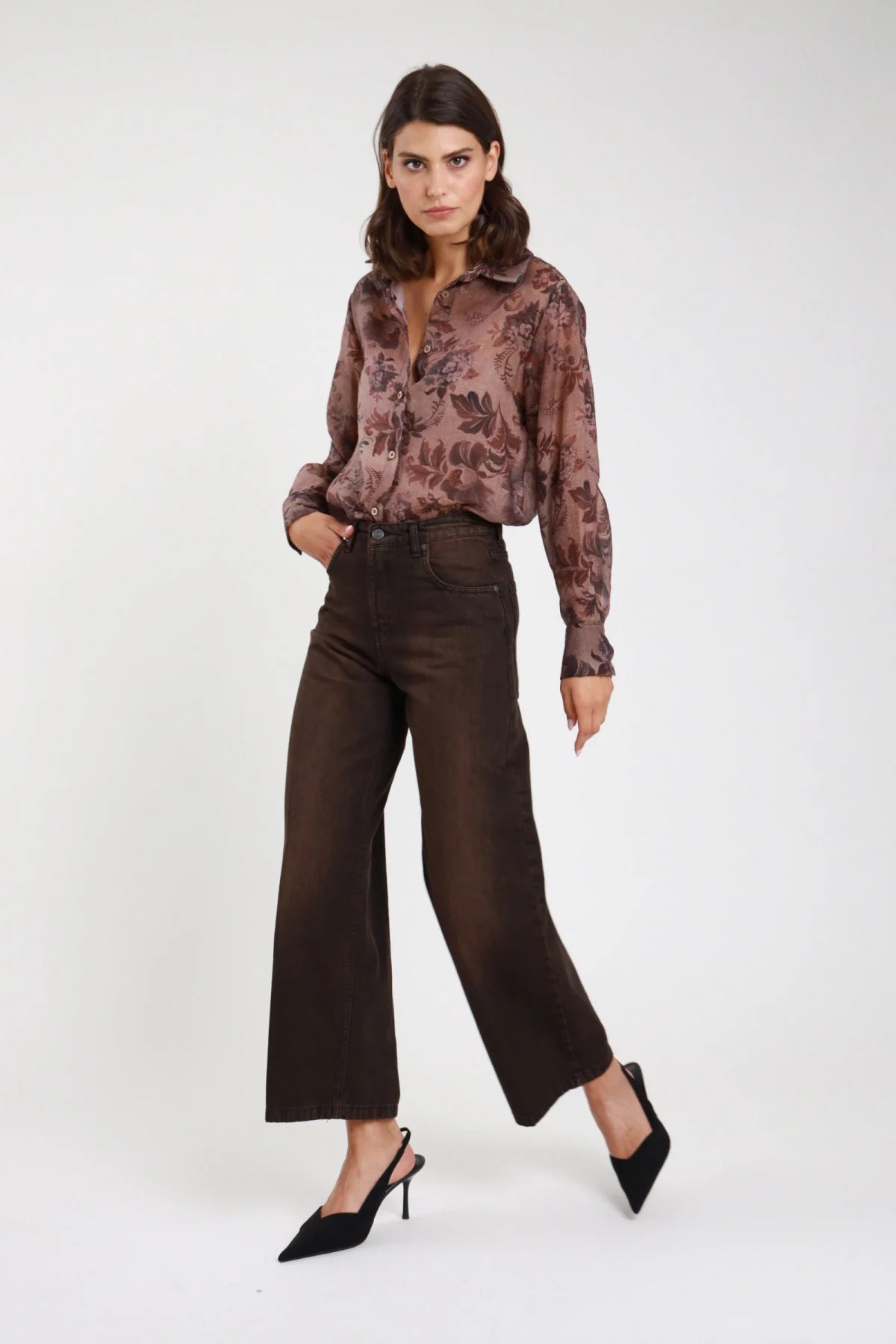 Jeans Cinzia wide leg marrone cioccolato donna vita alta gamba larga dritta fondo grezzo - vista frontale intera in movimento con camicia fantasia floreale e décolleté neri