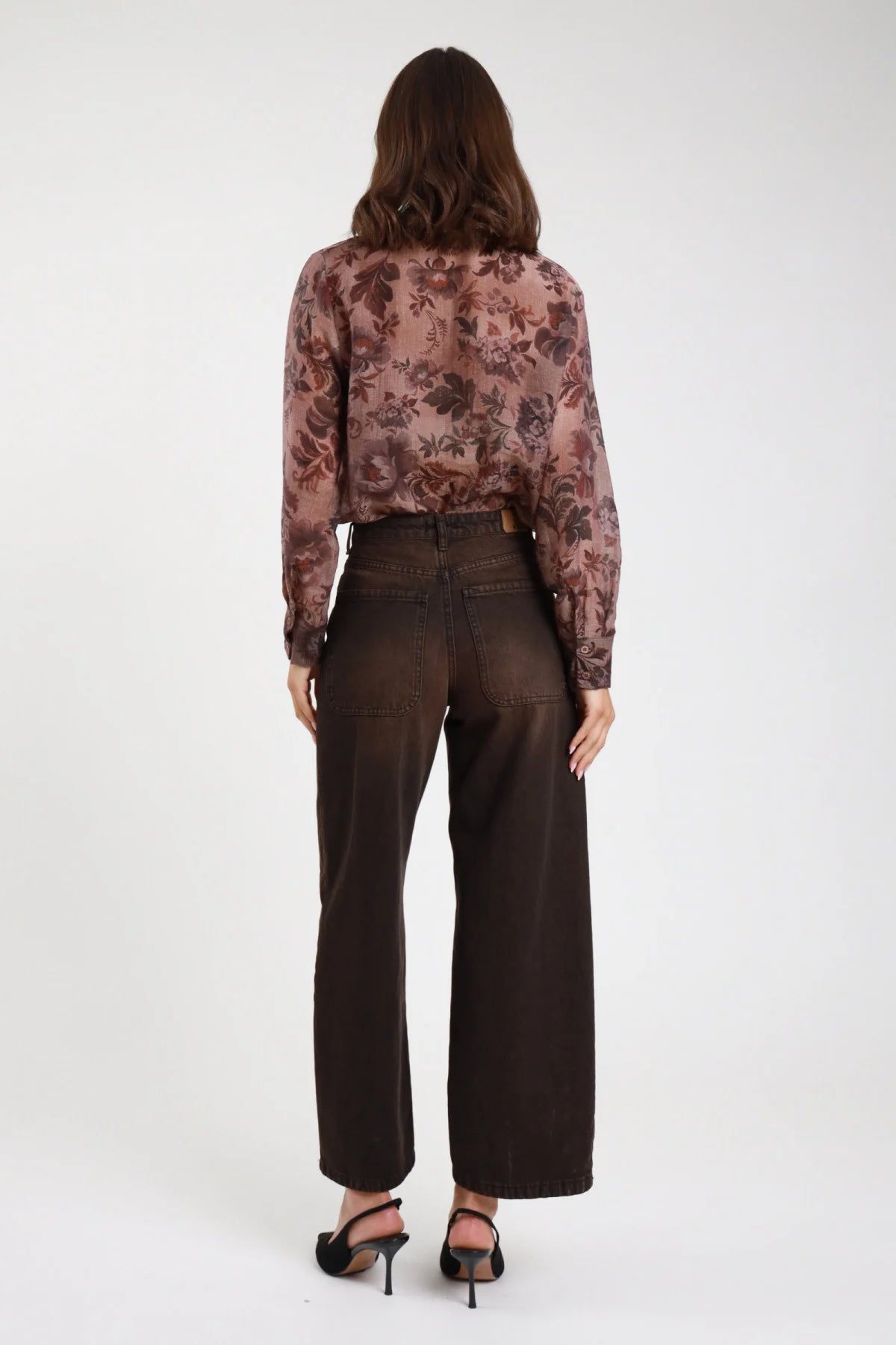 Jeans Cinzia wide leg marrone cioccolato donna vita alta cuciture contrasto arancio posteriore gamba larga fondo grezzo - vista posteriore intera con camicia fantasia floreale e décolleté neri