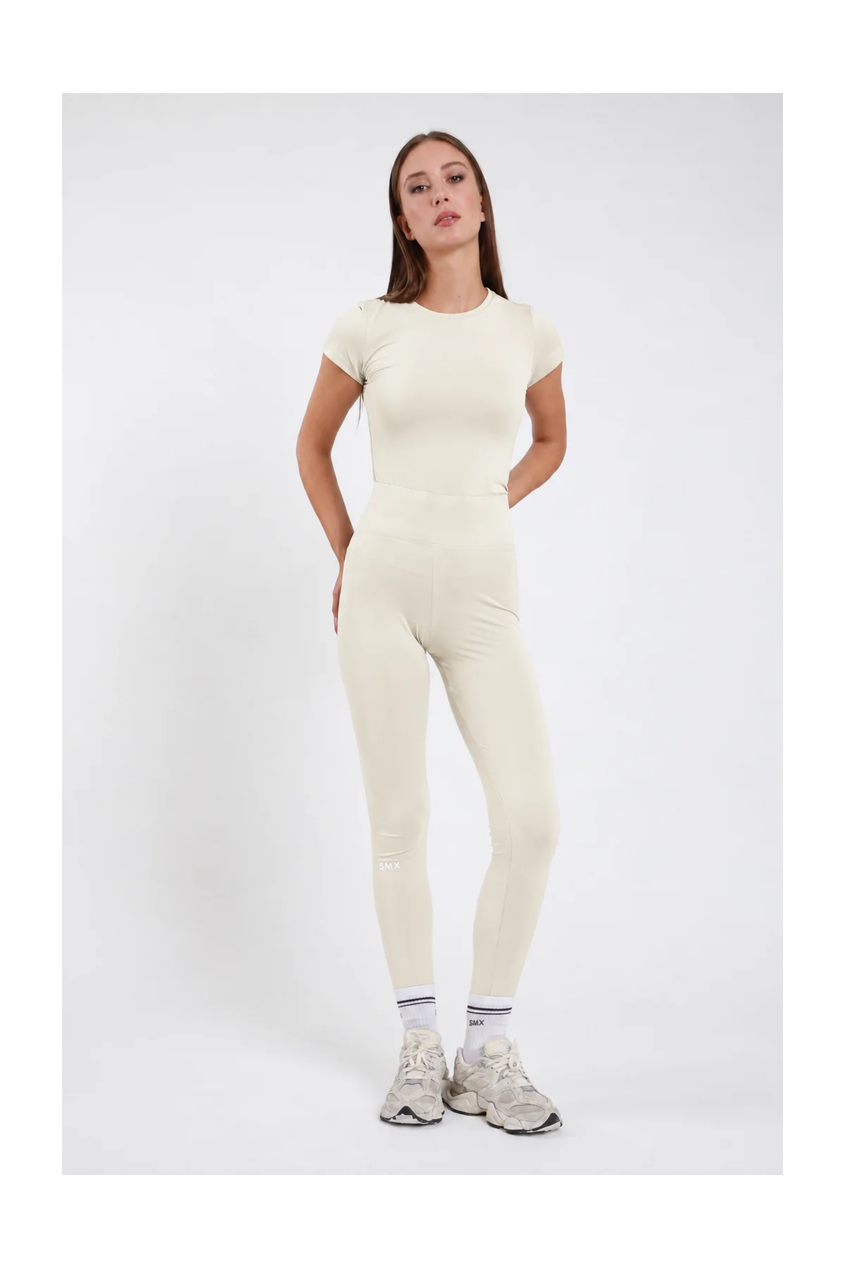 Leggings Body-Line DAYTHRU panna avorio vita alta elastica logo SMX polpaccio full-length second-skin frontale intera posa statica mano fianco sguardo frontale - modella frontale intera posa statica mano fianco sguardo frontale capelli castani lisci sfondo bianco t-shirt manica corta panna coordinata sneakers beige calze bianche SMX