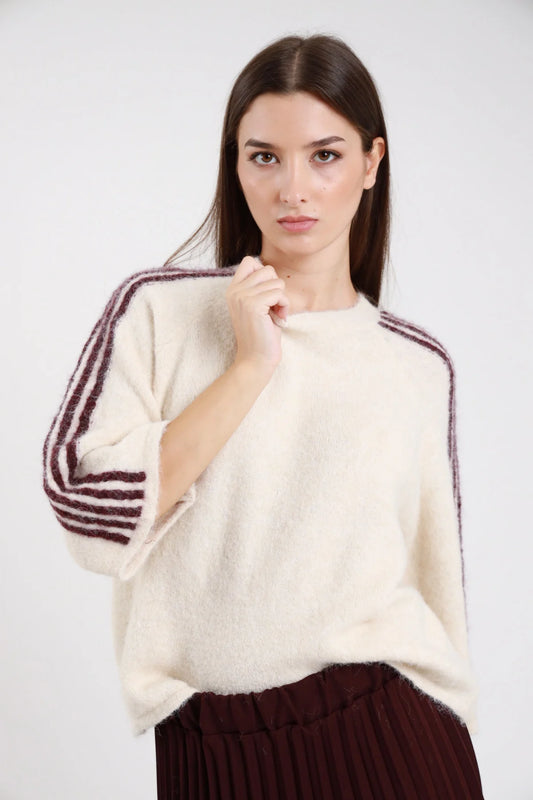 Pullover bande strisce contrasto manica panna ecru off-white corpo bande bordeaux prugna verticali 3-4 righe alternate batwing dolman manica 3/4 girocollo oversize boxy vita orlo dritto maglia bouclé alpaca-like - modella frontale busto tre quarti mano petto sguardo frontale intenso capelli castani lisci sfondo bianco gonna plissé bordeaux