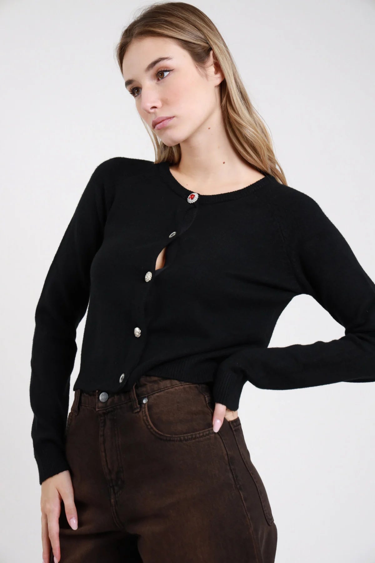 Cardigan Crop Bottoni Gioiello grigio melange 49% viscosa girocollo bottoni gioiello misti manica lunga costina fitted crop dettaglio frontale - modella busto frontale sguardo laterale capelli biondi ondulati sfondo bianco pantaloni bordeaux prugna