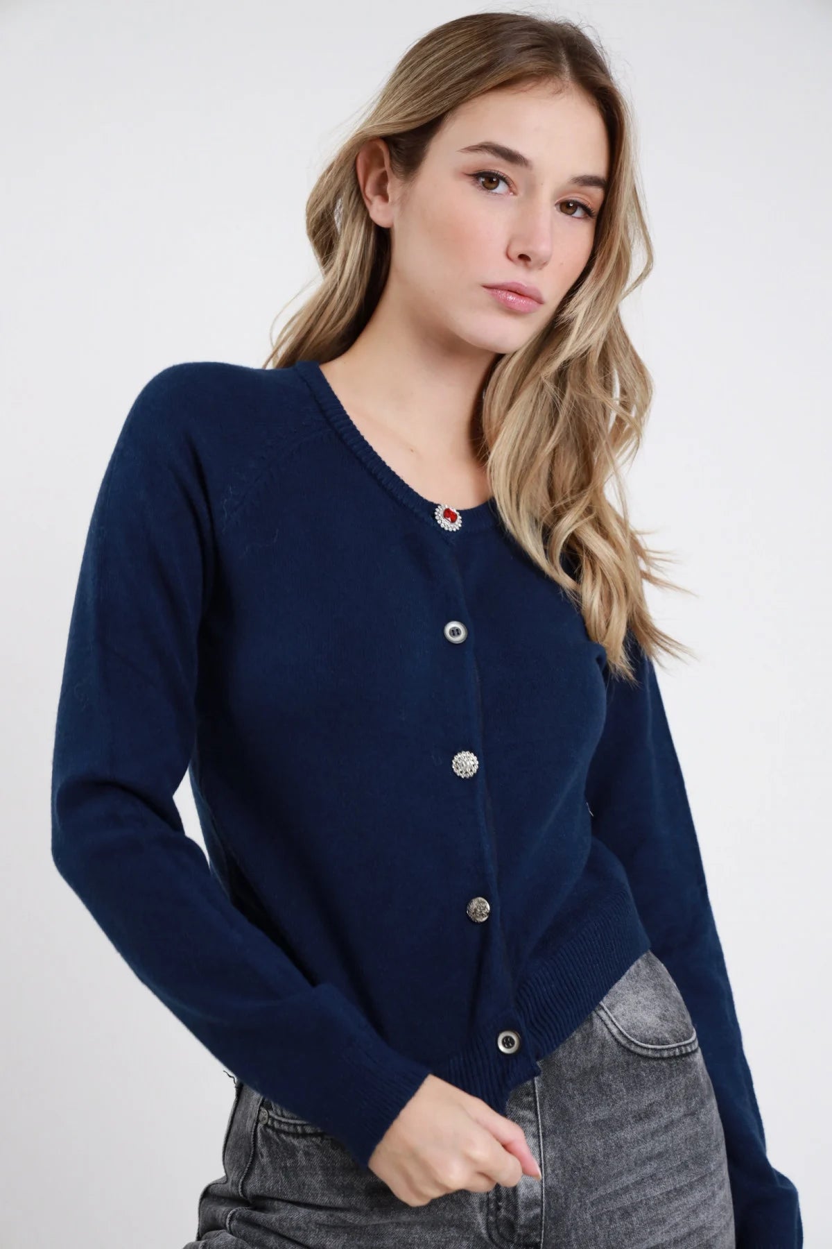 Cardigan Crop Bottoni Gioiello grigio melange 49% viscosa girocollo ampio bottoni gioiello misti bruniti argentati dorati manica lunga bordo costina fitted crop laterale - modella busto 3/4 laterale mano orecchio sguardo 3/4 capelli biondi ondulati sfondo bianco pantaloni bordeaux prugna