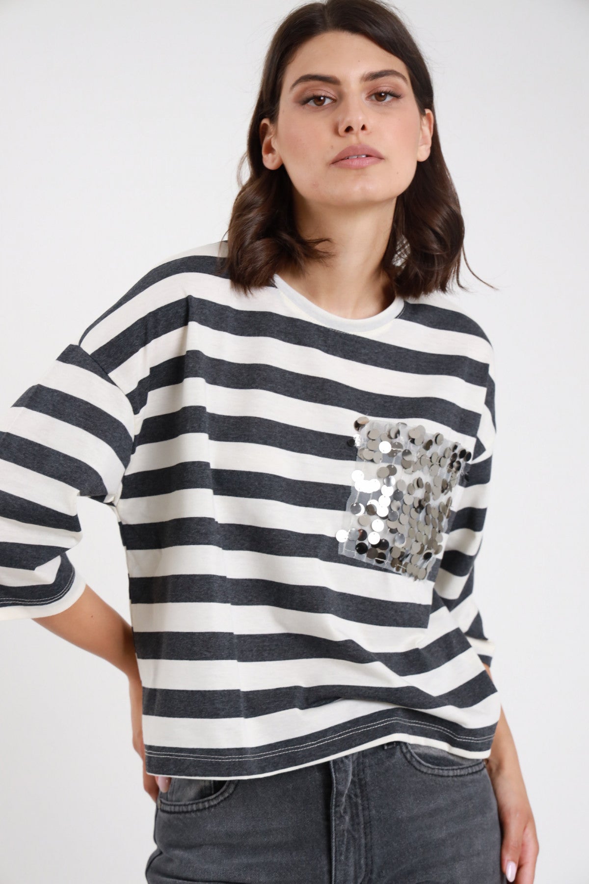T-shirt Taschina Paillettes argento maxi righe marinière bianco panna grigio antracite oversize boxy crop collo rotondo manica 3/4 busto frontale mano fianco - modella busto frontale mano fianco sguardo frontale capelli castani ondulati sfondo bianco jeans grigio denim