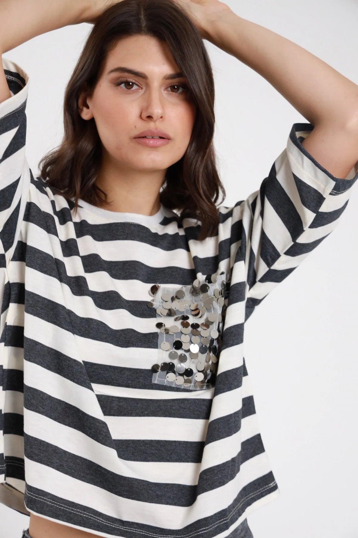 T-shirt Taschina Paillettes argento maxi righe marinière bianco panna grigio antracite oversize boxy dettaglio taschino paillettes busto frontale braccia alzate - modella busto frontale braccia alzate sguardo frontale capelli castani ondulati sfondo bianco