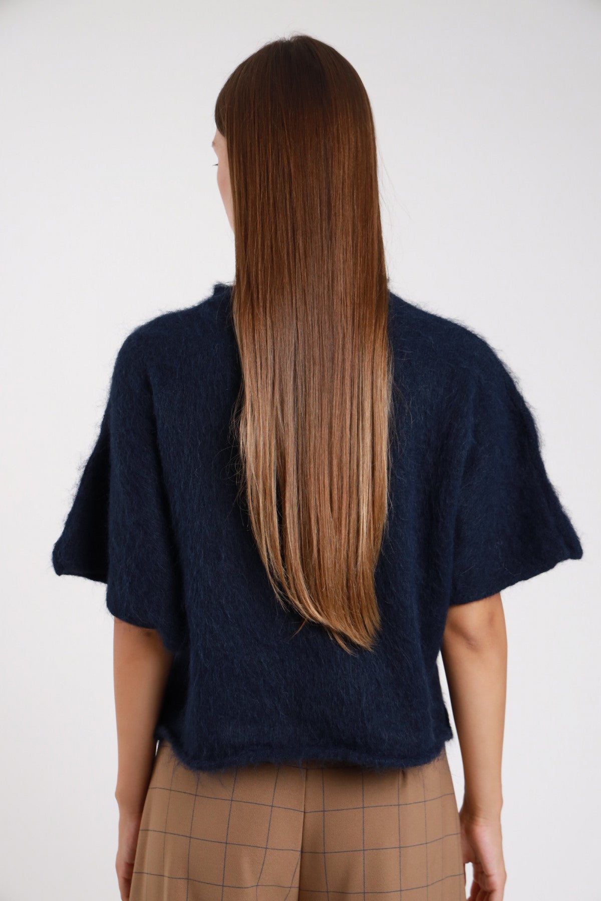 Pullover maniche corte navy blu notte mock-neck oversize crop dinamico secondo angolo - modella busto frontale mani ai fianchi sguardo frontale pantalone quadri cammello capelli castani