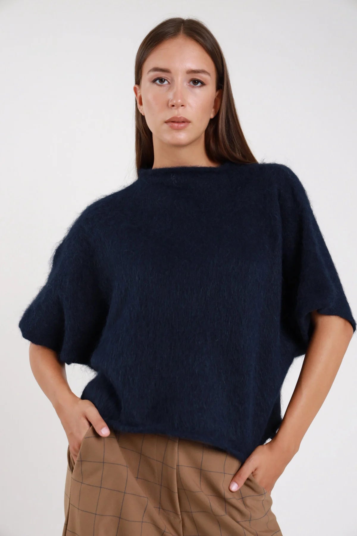 Pullover maniche corte azzurro baby blue maglia mohair spazzolata mock-neck crop - modella busto frontale mani sull orlo sguardo frontale gonna grigio scuro capelli castani raccolti