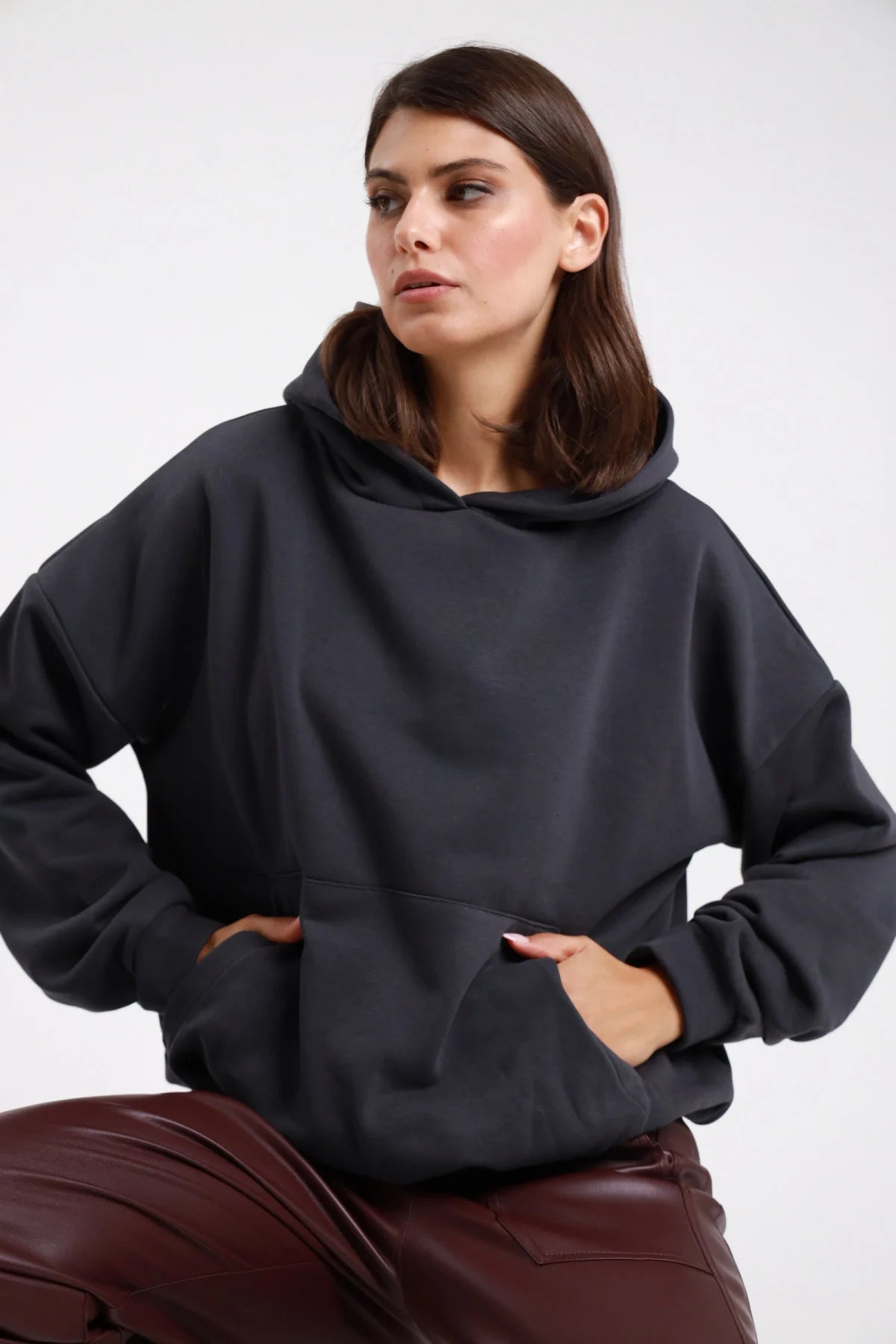 Felpa cappuccio nero antracite donna oversize cropped cappuccio ampio tasca marsupio maniche lunghe polsino costine - vista frontale tre quarti mani in tasca con pantaloni bordeaux ecopelle