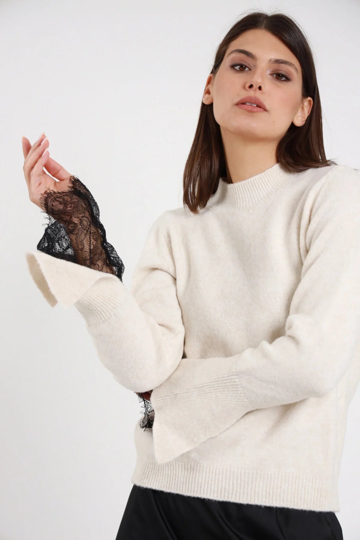 Pullover Manica Pizzo panna avorio crema 46% poliestere 8% lana girocollo manica lunga braccia incrociate pizzo nero floreale paisley volant molto visibile dettaglio manica frontale busto 3/4 - modella busto 3/4 braccia incrociate sguardo frontale capelli castani scuri lisci sfondo bianco gonna satin nera abbinata