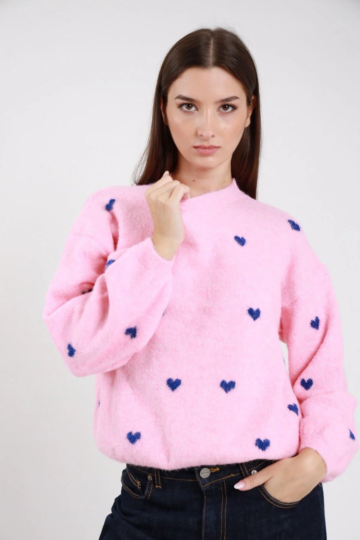 Pullover cuori jacquard tutto corpo eyelash bouclé balloon oversize girocollo costine rosa cipria cuori blu navy frontale busto mano pugno colletto - modella frontale busto mano pugno colletto sguardo frontale capelli castani scuri lisci sfondo bianco jeans blu scuro