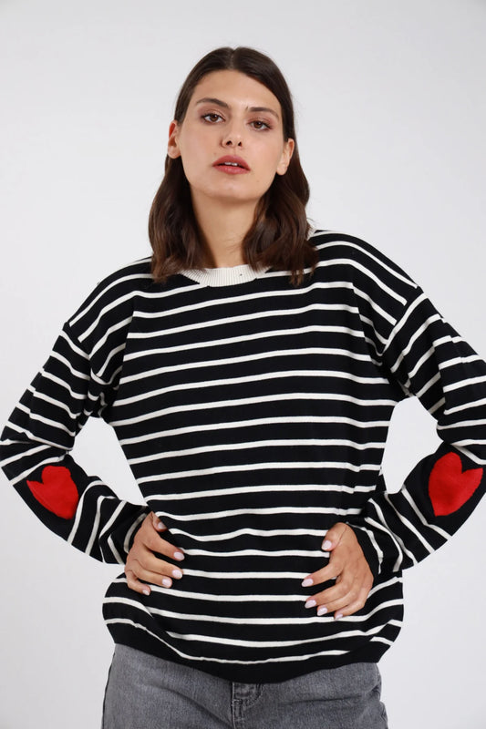 Pullover righe orizzontali bicolore cuori jacquard intarsiati gomiti nero bianco panna cuori rosso frontale mani fianchi - modella frontale mani fianchi sguardo frontale capelli castani scuri ondulati sfondo bianco jeans grigio scuro