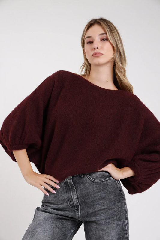 Pullover maniche pipistrello bordeaux vino batwing girocollo maglia bouclé - modella frontale intera mani sui fianchi sguardo frontale jeans grigi capelli biondi mossi