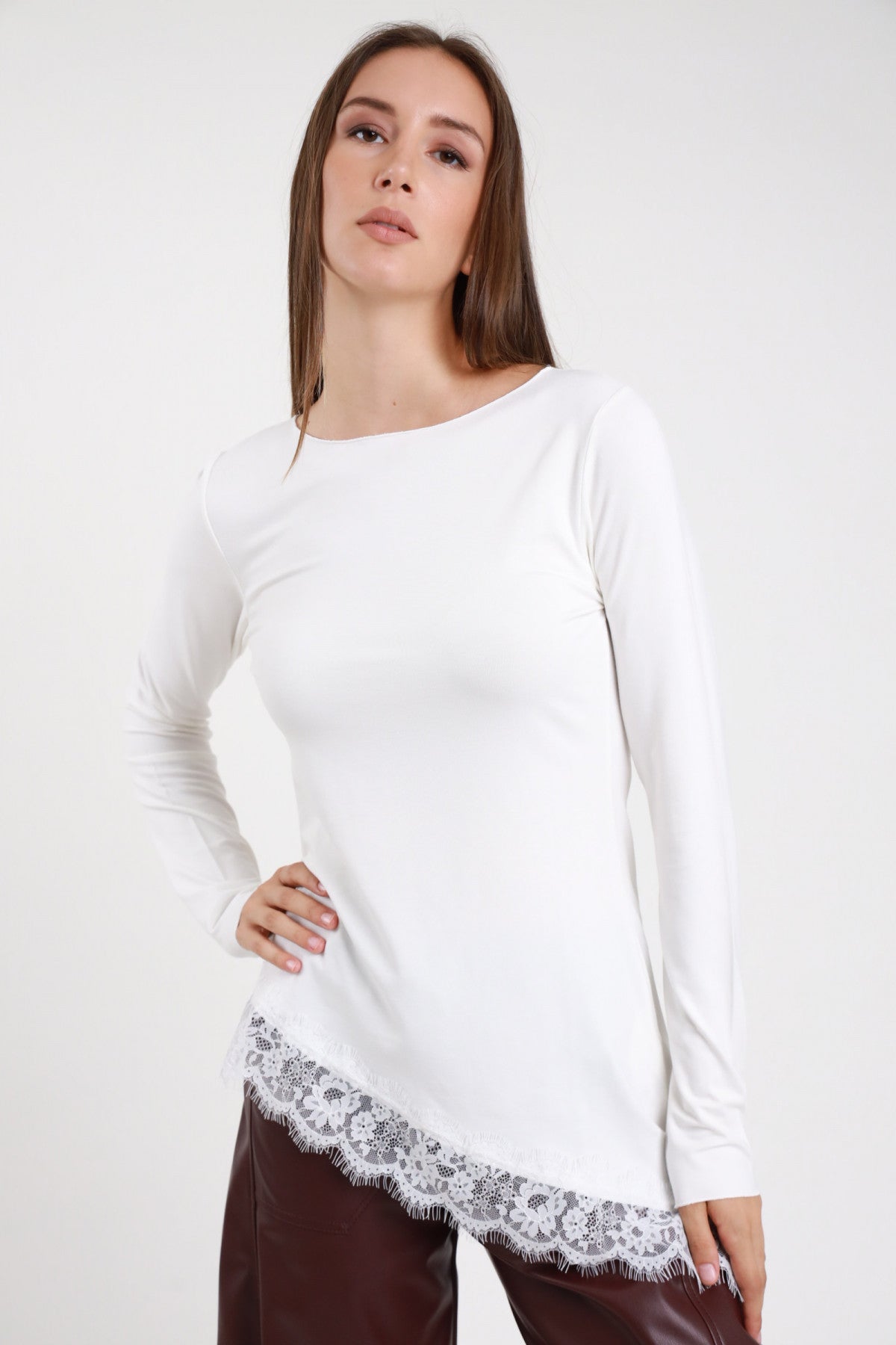 Maglia pizzo asimmetrica bianca panna donna collo barchetta maniche lunghe bordo pizzo floreale tono su tono - vista frontale mano sul fianco con pantaloni in ecopelle bordeaux