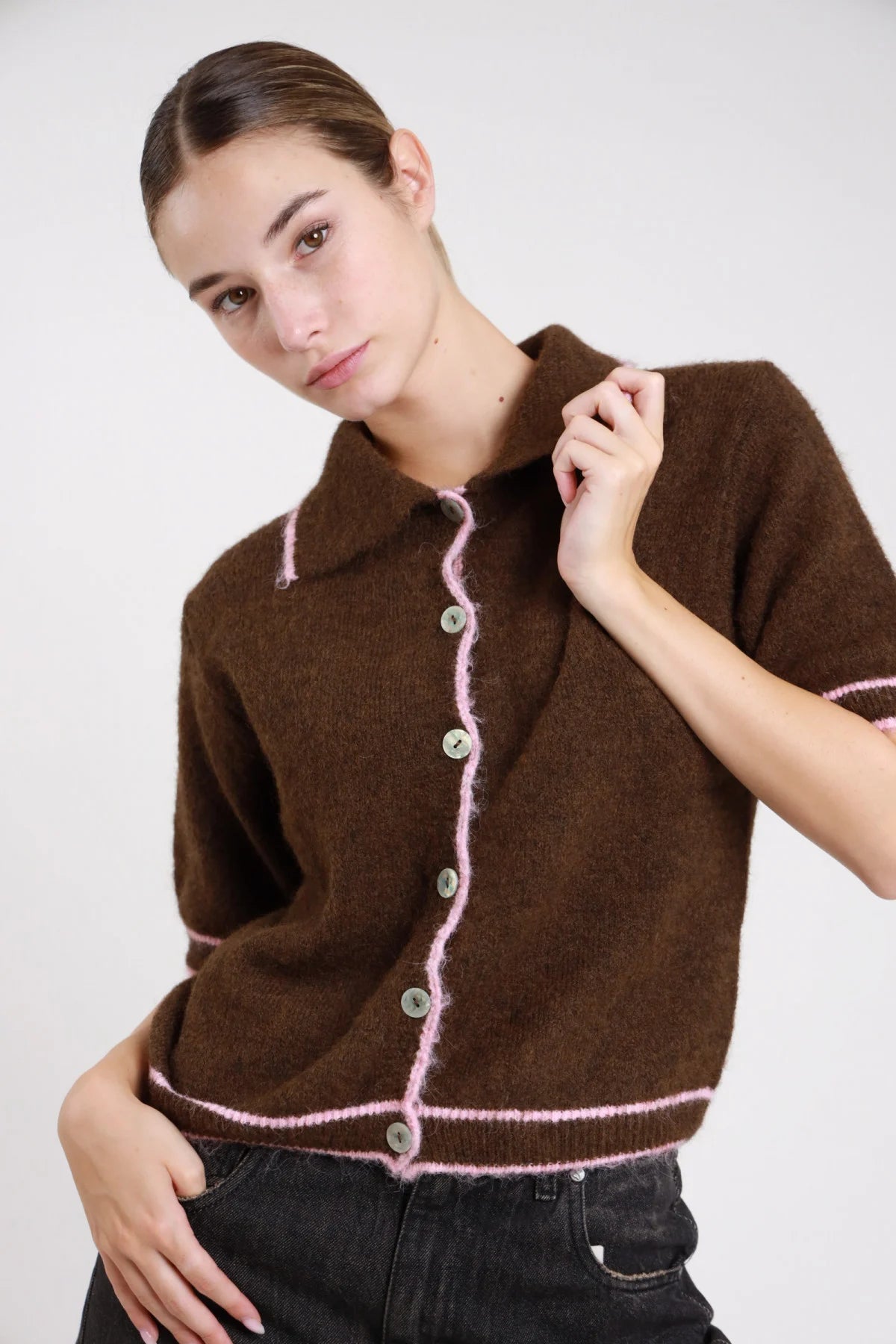 Polo maglia boucle nero bordino eyelash bianco panna frontale busto mani vita colletto polo punta abbottonatura bottoni madreperla bordino wavy manica corta - modella frontale busto mani vita sguardo frontale pantaloni animalier capelli biondi mossi