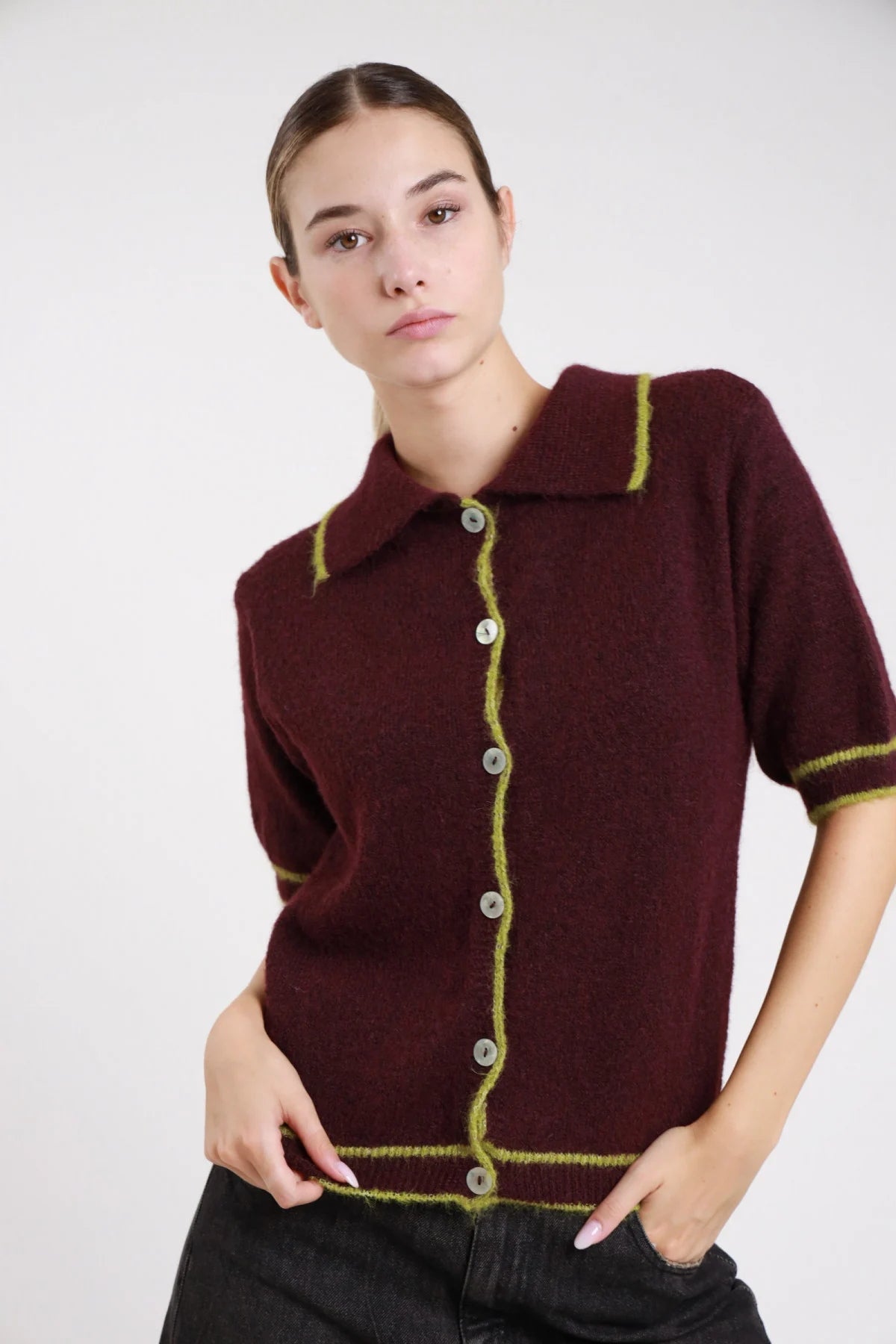 Polo maglia boucle nero bordino eyelash bianco panna frontale tre quarti mano testa alzata colletto polo bordino wavy ondulato manica corta dropped shoulder orlo crop - modella frontale tre quarti mano testa alzata sguardo alto laterale pantaloni animalier capelli biondi mossi
