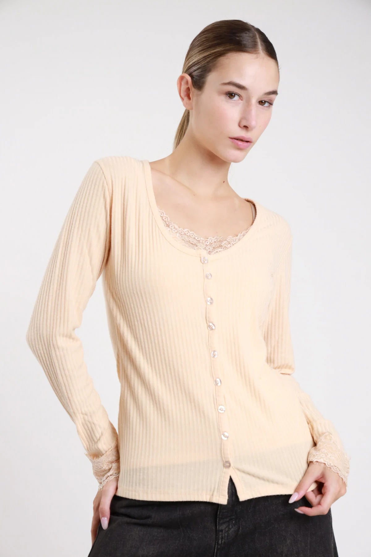Set cardigan canotta costina panna crema pizzo floreale - modella busto tre quarti jeans neri mano in tasca capelli raccolti coda