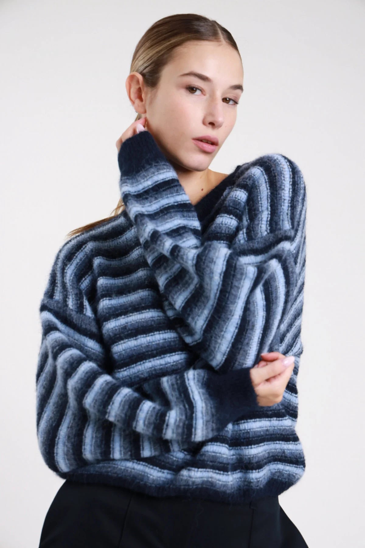 Maglione righe multicolor wave navy azzurro grigio blu frontale busto braccia conserte turtleneck collo alto costina navy manica - modella frontale busto braccia conserte mano collo sguardo frontale pantaloni neri capelli biondi raccolti