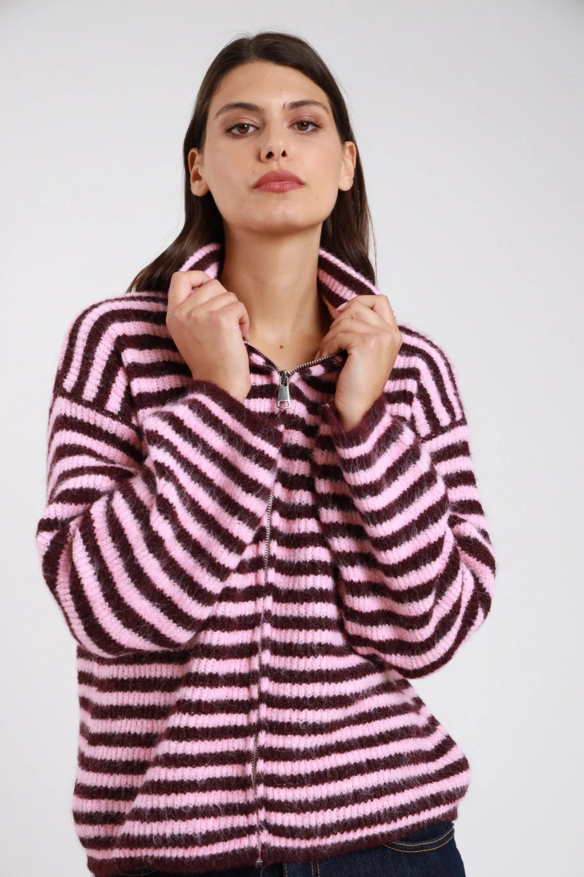 Felpa maglia bouclé eyelash righe bold bicolor rosa cipria bordeaux vinaccia zip frontale argento funnel neck oversize boxy frontale busto mani collo zip - modella frontale busto mani collo zip sguardo frontale capelli castani scuri lisci sfondo bianco jeans blu