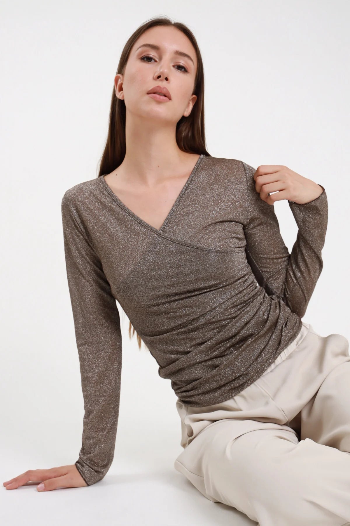 Maglia incrocio lurex bronzo marrone donna scollo V portafoglio drappeggio laterale - vista seduta con pantaloni beige