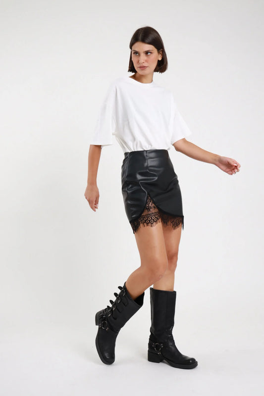 Minigonna ecopelle pizzo Susy Mix nera con orlo incrociato, indossata con T-shirt bianca e stivali neri