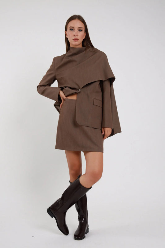 Minigonna sartoriale marrone cioccolato vita alta mini dritta tubino stretch zip laterale frontale 3/4 posa laterale coordinata blazer mantella marrone - modella frontale 3/4 posa laterale sguardo camera capelli castani lisci sfondo bianco blazer mantella marrone stivali neri alti ginocchio tacco basso