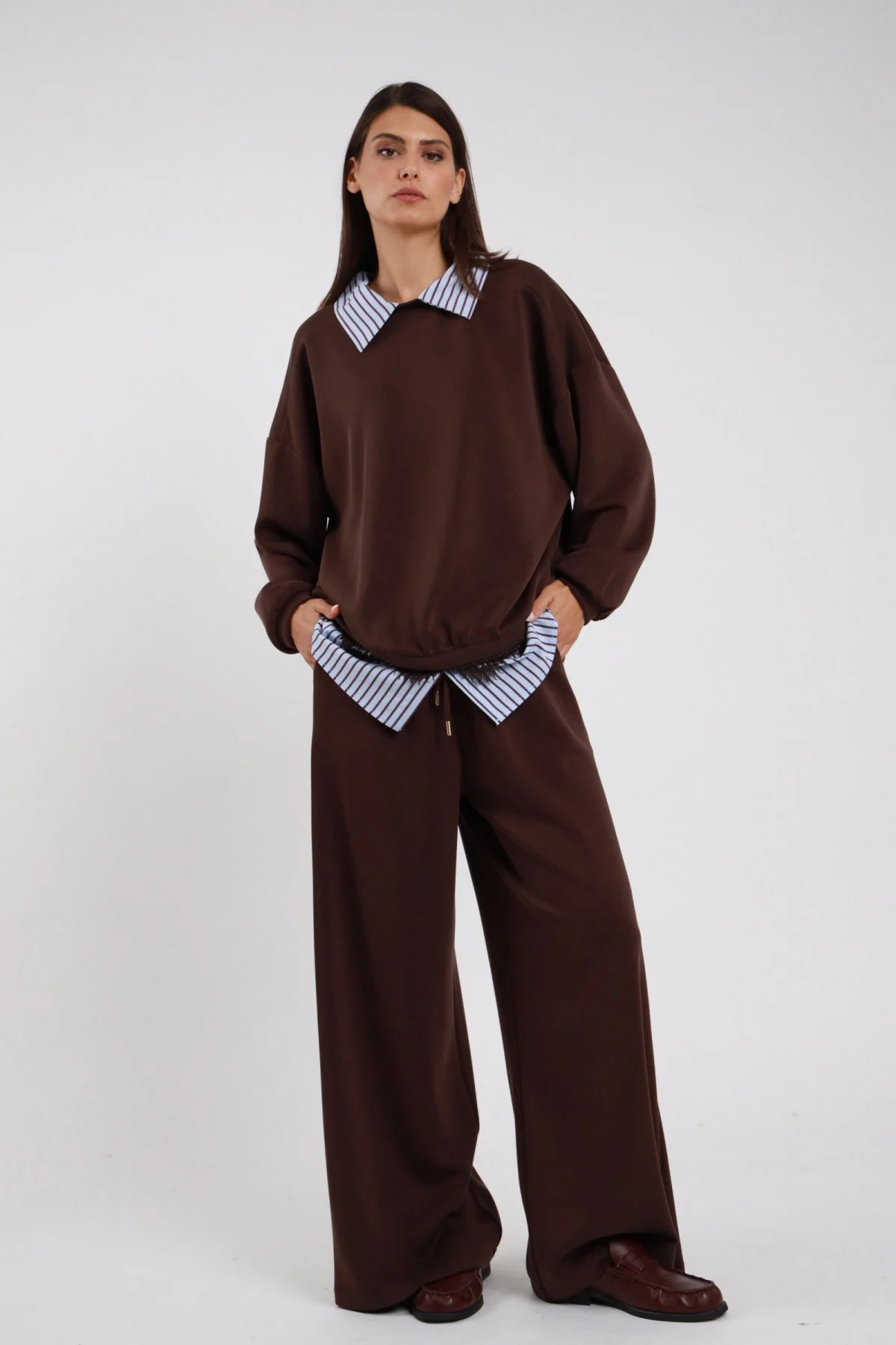 Pantaloni Wide Leg Coulisse Camicia Righe marrone cioccolato 48% rayon coulisse cordino vita striscia camicia righe blu bianco fuoriesce gamba wide leg larghissima caduta fluida frontale intera - modella intera frontale mani tasche sguardo frontale intenso capelli castani lisci sfondo bianco felpa marrone coordinata scarpe marrone