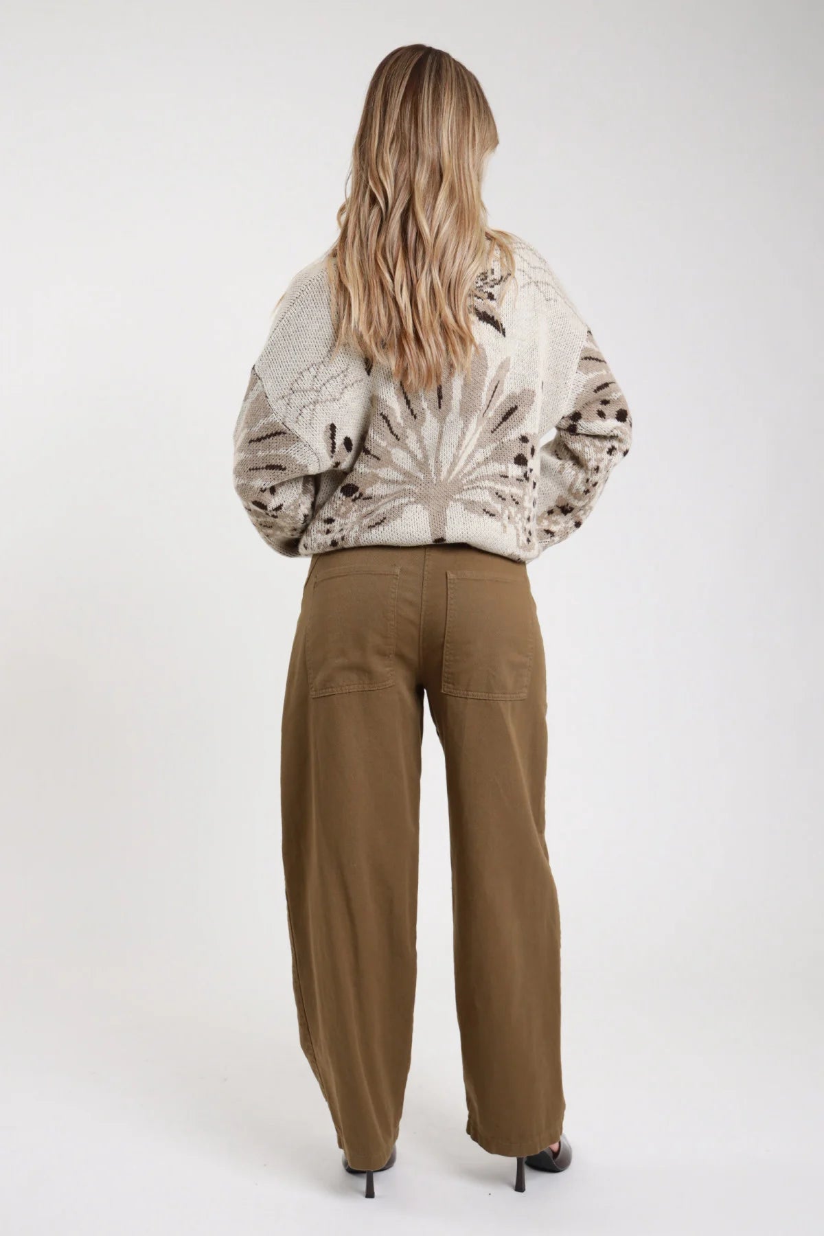Jeans Tinto Capo Tasconi verde oliva khaki wide barrel tasche posteriori vita alta retro intera schiena - modella retro intera capelli biondi ondulati sfondo bianco cardigan fantasia beige décolleté nere