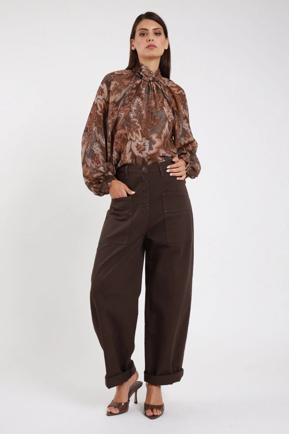 Jeans Tinto Capo Tasconi marrone cioccolato scuro wide barrel tasconi applicati vita alta risvolto frontale intera mano tasca - modella frontale intera mano tasca sguardo frontale capelli castani lisci sfondo bianco blusa paisley marrone sandali marroni tacco