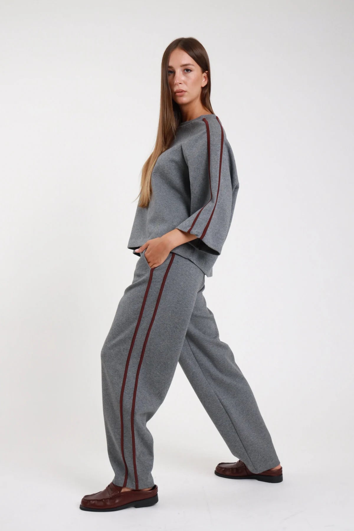 Pantalone barrel bande grigio melange frontale intera coordinato felpa bande borgogna vita elastica coulisse tasche laterali gamba barrel - modella frontale intera mani tasche sguardo frontale felpa grigia bande borgogna loafer bordeaux capelli castani lisci
