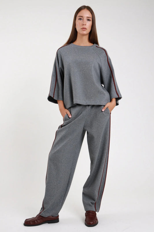 Pantalone barrel bande grigio melange retro intera coordinato felpa grigia bande borgogna gamba barrel carrot orlo dritto full length - modella retro intera sguardo basso laterale felpa grigia bande borgogna loafer bordeaux capelli castani lisci