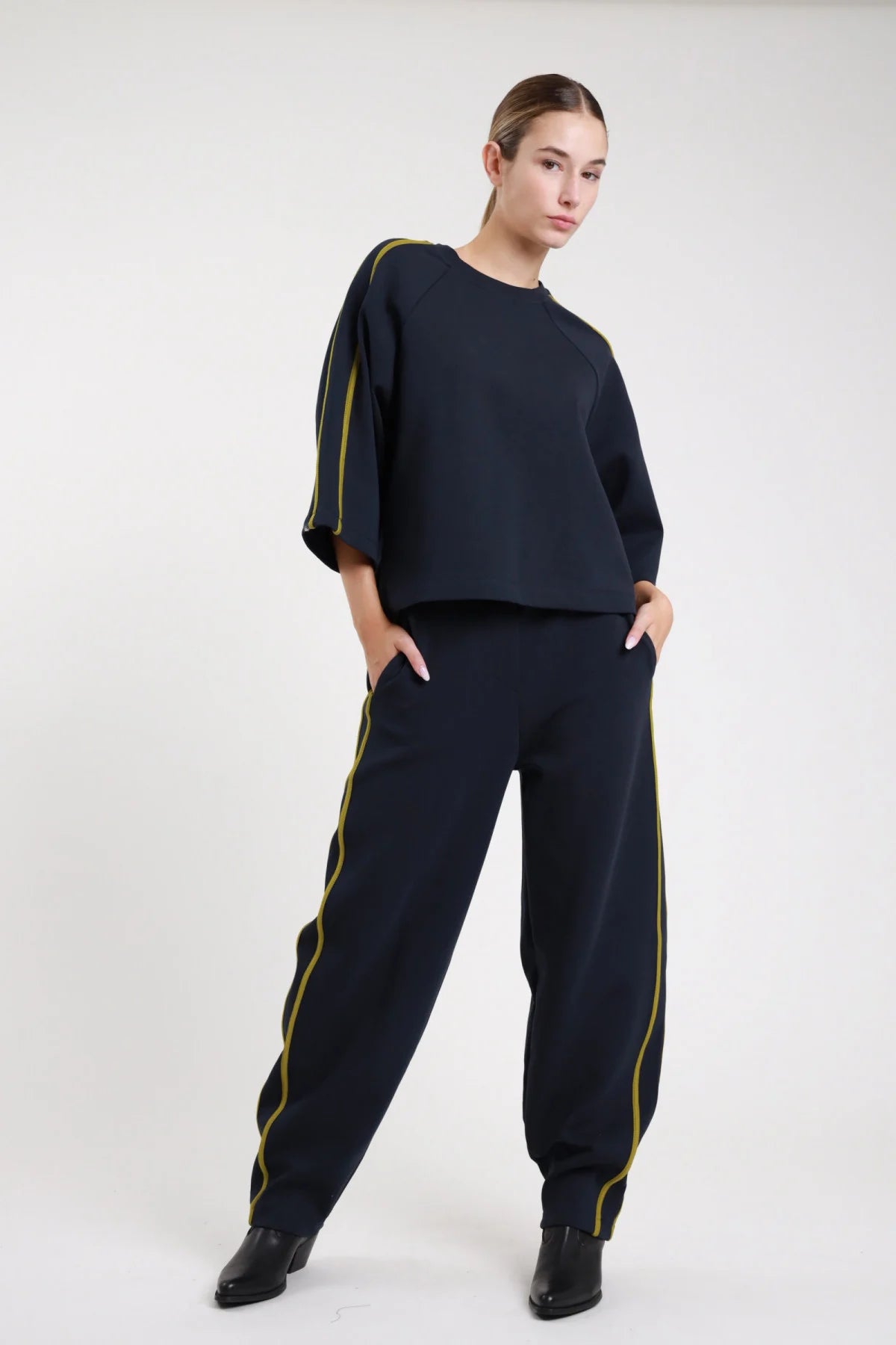 Pantalone barrel bande cioccolato moro frontale intera coordinato felpa cioccolato bande panna vita elastica gamba carrot full length - modella frontale intera mani tasche sguardo frontale felpa cioccolato bande panna décolleté marroni capelli castani raccolti