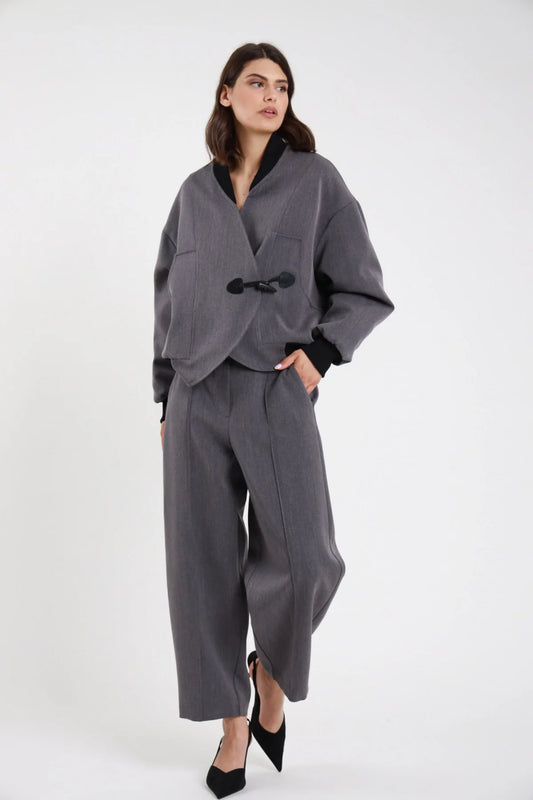 Pantalone Ovetto barrel grigio melange vita alta pinces tasche filetto gamba balloon scultorea cropped 7/8 frontale intera con Bomber Alamaro grigio melange alamaro nero - modella frontale intera sguardo laterale capelli castani scuri sfondo bianco bomber grigio melange slingback neri tacco