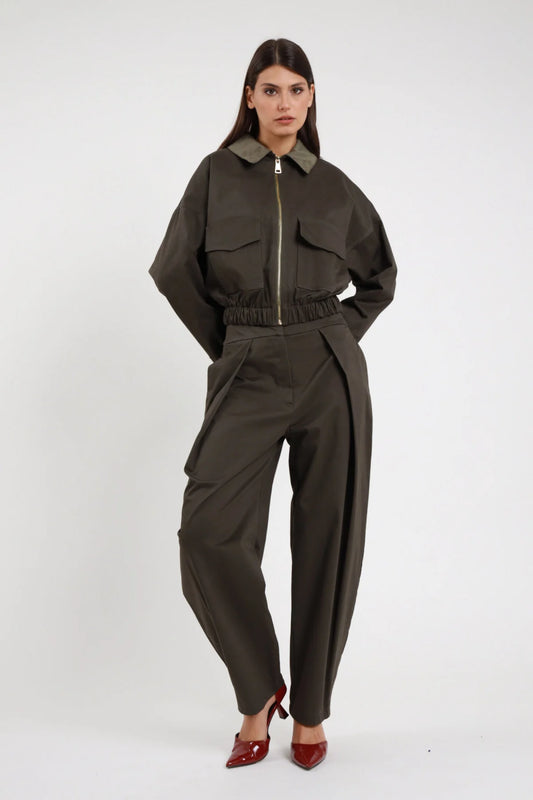 Pantalone piega Susy Mix Pre-Fall verde militare khaki 80% cotone 17% viscosa 3% elastan pince frontale strutturata vita alta gamba barrel ovetto tasche laterali fondo caviglia frontale intera mani tasche - modella intera frontale mani tasche sguardo frontale capelli scuri lisci sfondo bianco giacca crop zip stesso tessuto verde militare coordinata tacchi spillo bordeaux rosso abbinati