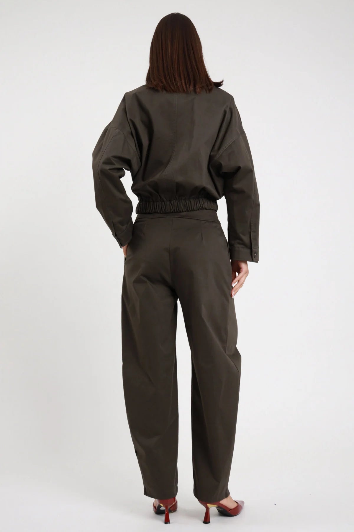 Pantalone piega Susy Mix Pre-Fall verde militare pince frontale vita alta elastico smock retro ben visibile gamba barrel ovetto fondo caviglia posteriore intera - modella intera posteriore capelli scuri lisci sfondo bianco elastico arricciato retro vita dettaglio giacca crop zip verde militare coordinata tacchi spillo bordeaux abbinati