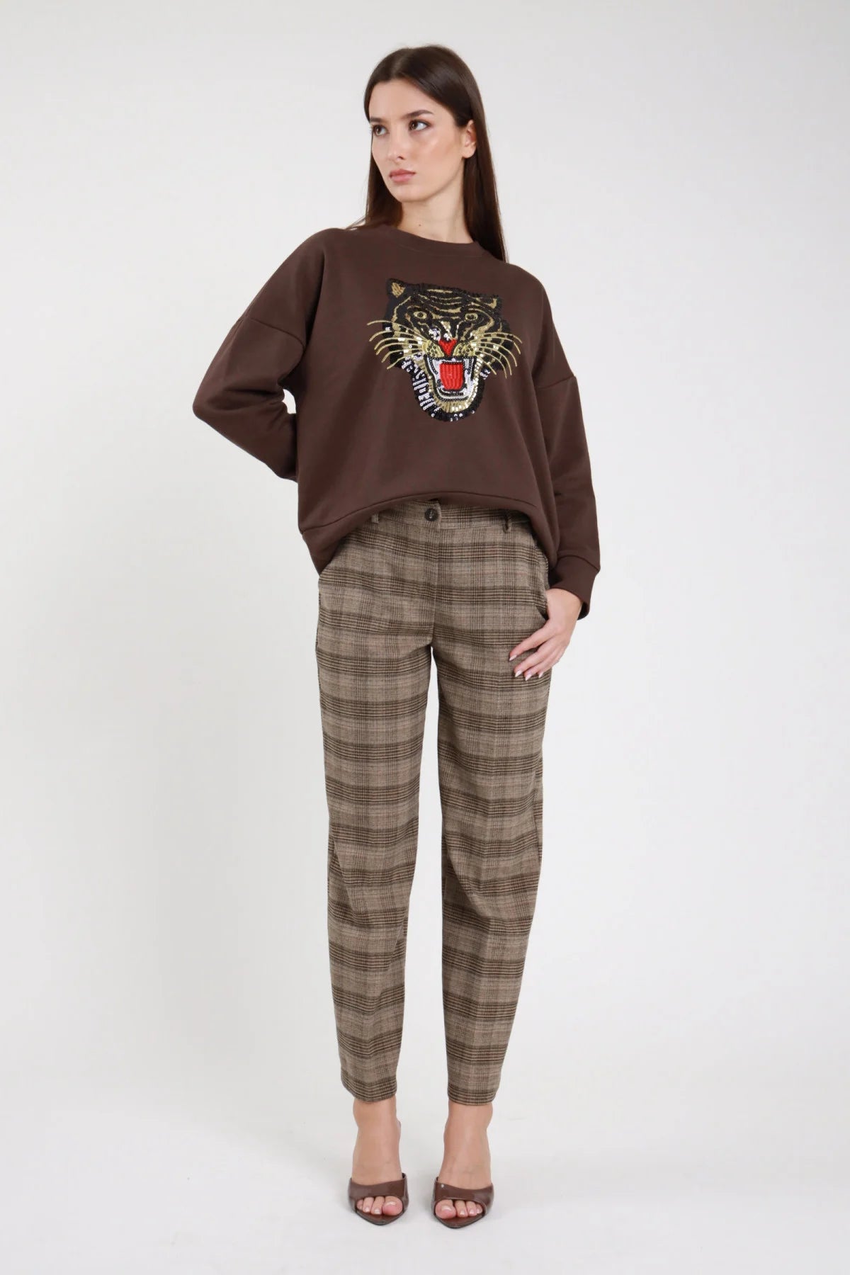 Pantaloni check principe di Galles sartoriali beige marrone nero gamba dritta straight piega centrale vita media tasche filetto caviglia frontale intera look completo felpa tigre paillettes - modella frontale intera sguardo frontale capelli castani lisci lunghi sfondo bianco mules tacco marroni felpa marrone tigre paillettes