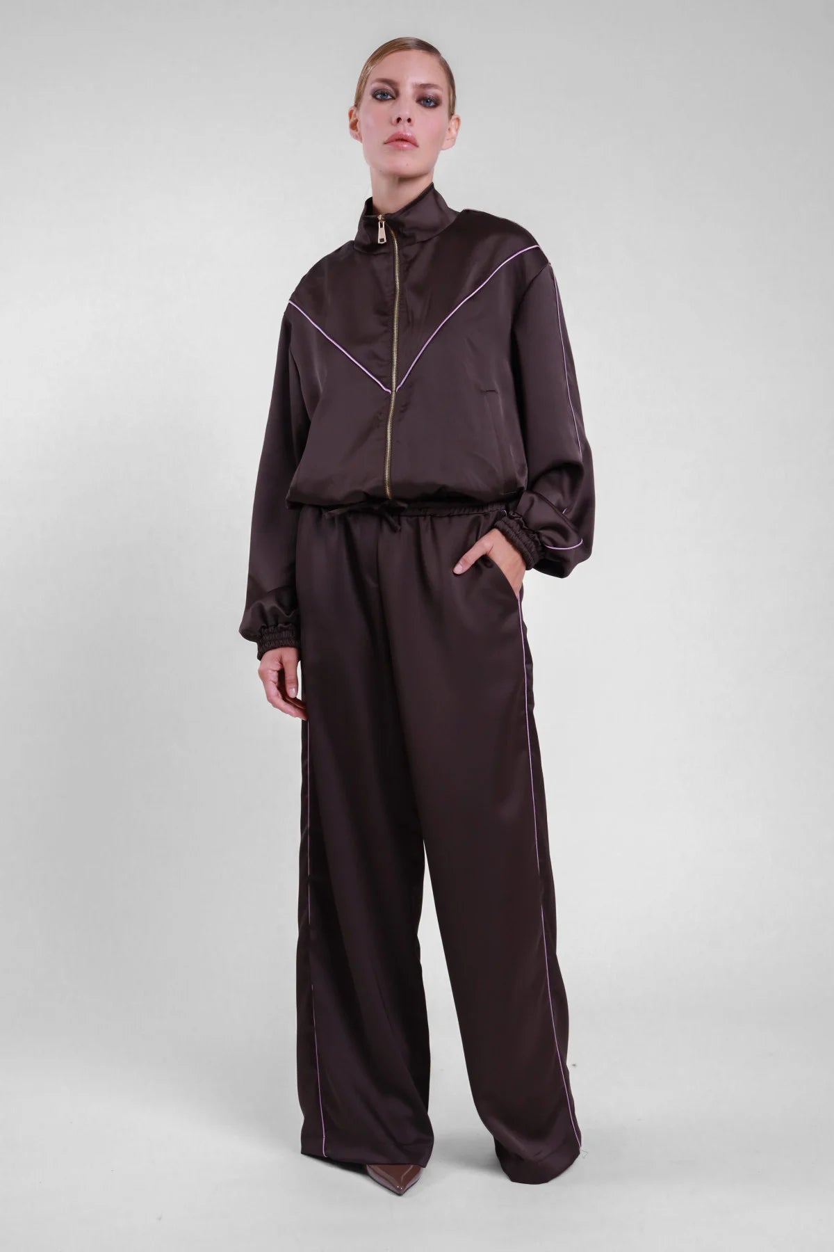 Pantalone piping Susy Mix marrone scuro con profili laterali chiari, indossato con bomber coordinato