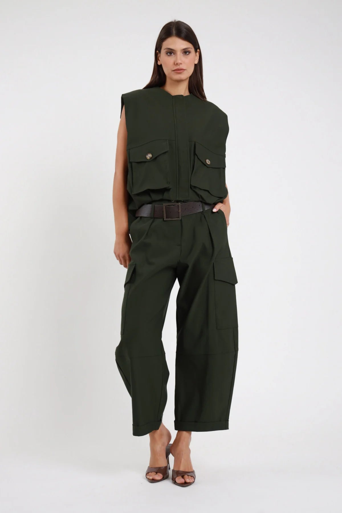 Pantalone Cargo Tasconi Vita Alta verde militare bottiglia 78% viscosa vita alta passanti cintura larga pieghe davanti 2 tasconi laterali cargo bottone risvolto fondo gamba barrel ballon cropped frontale intera - modella intera frontale posa mano tasca sguardo frontale intenso capelli castani lisci sfondo bianco gilet verde coordinato cintura ecopelle marrone sandalo mule marrone tacco